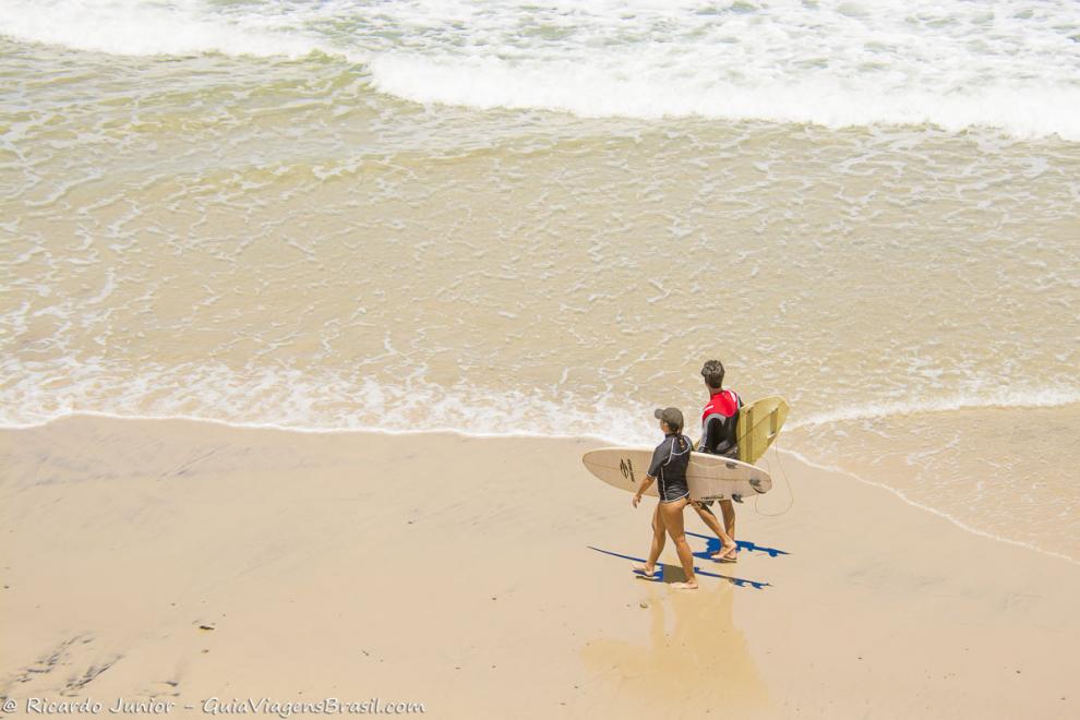 Imagem casal de surfistas entrando no mar da Praia da Engenhoca.